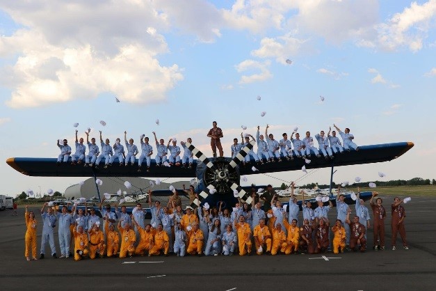 Les candidats du Hop ! Tour des jeunes pilotes posent devant un avion avant le début de cette expérience, accompagnés de leurs instructeurs de vol.
